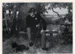 Heilbuth, Ferdinand , A young man seated on a bench in the country with his Terrier